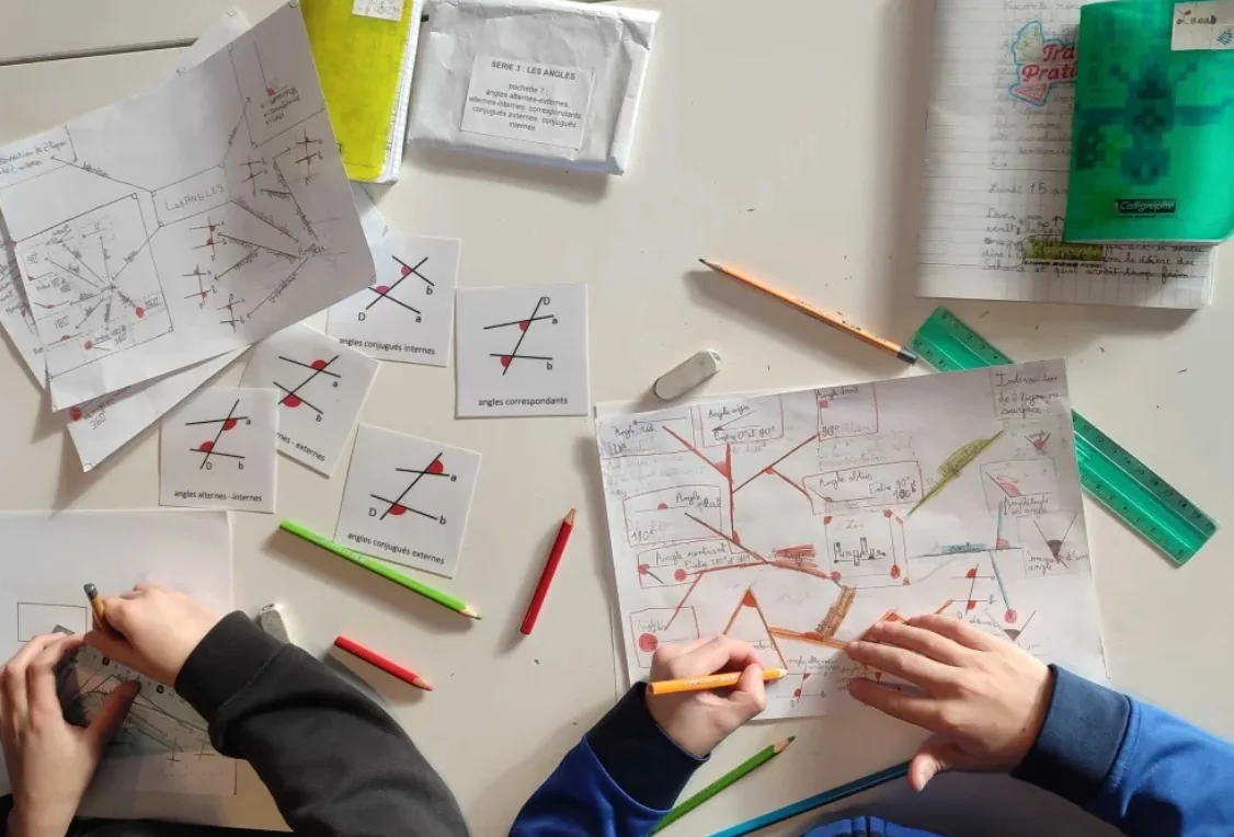 Des enfants étudient les angles à l’aide de cartes, de dessins et de leurs cahiers.