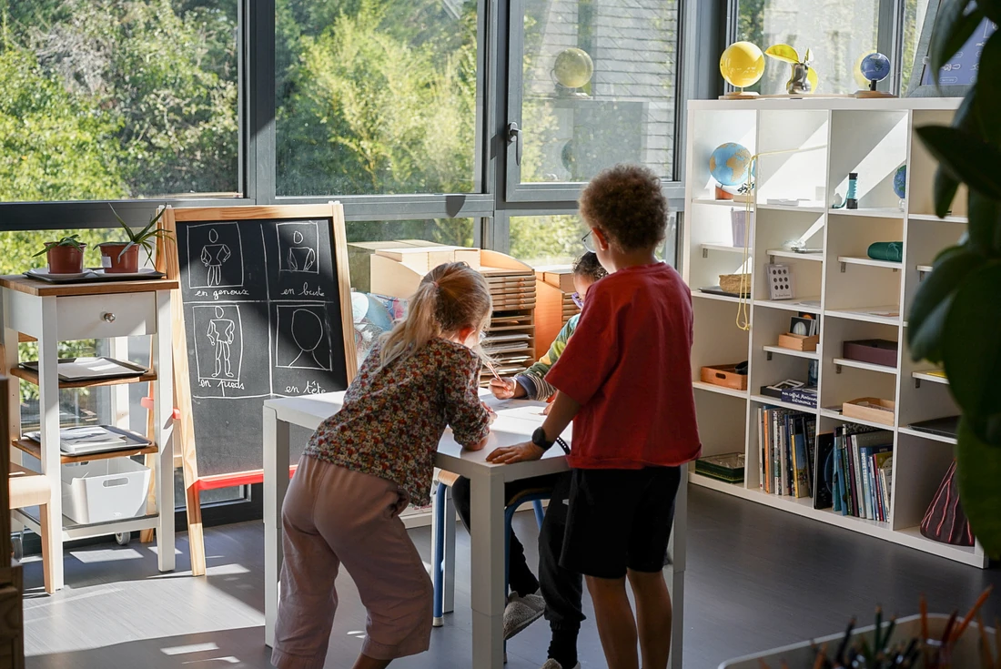 Des enfants travaillent ensemble autour d’une table dans une ambiance lumineuse.