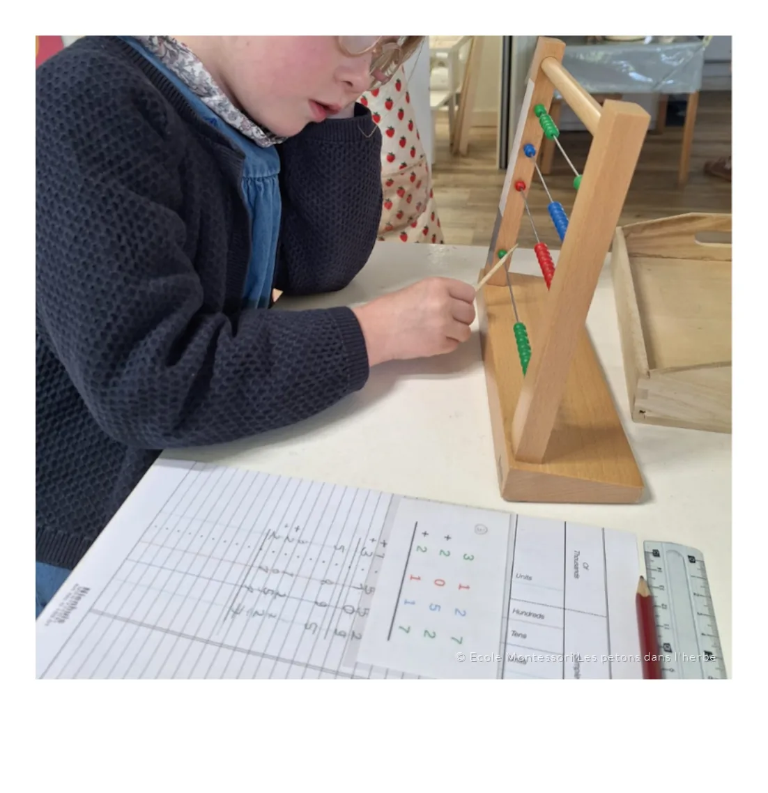 Un enfant manipule les perles d’un boulier Montessori pour calculer.