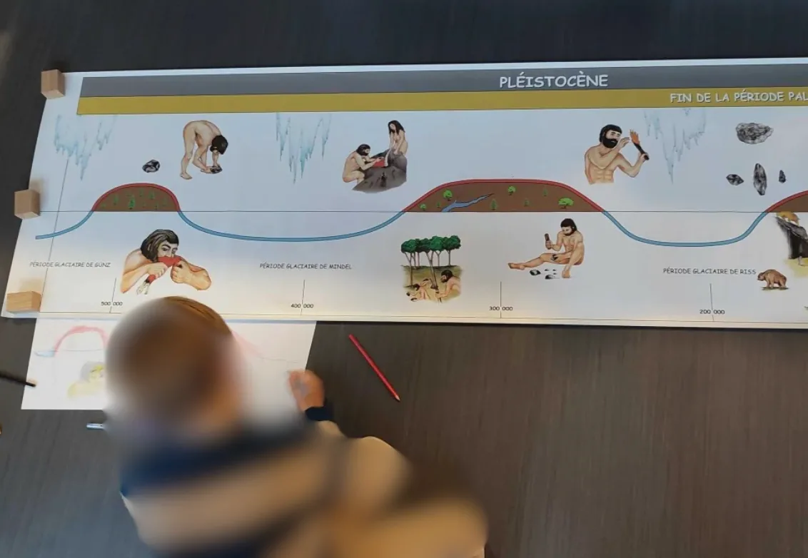 Un enfant observe une frise de la préhistoire dans l’ambiance ; son visage est flouté.